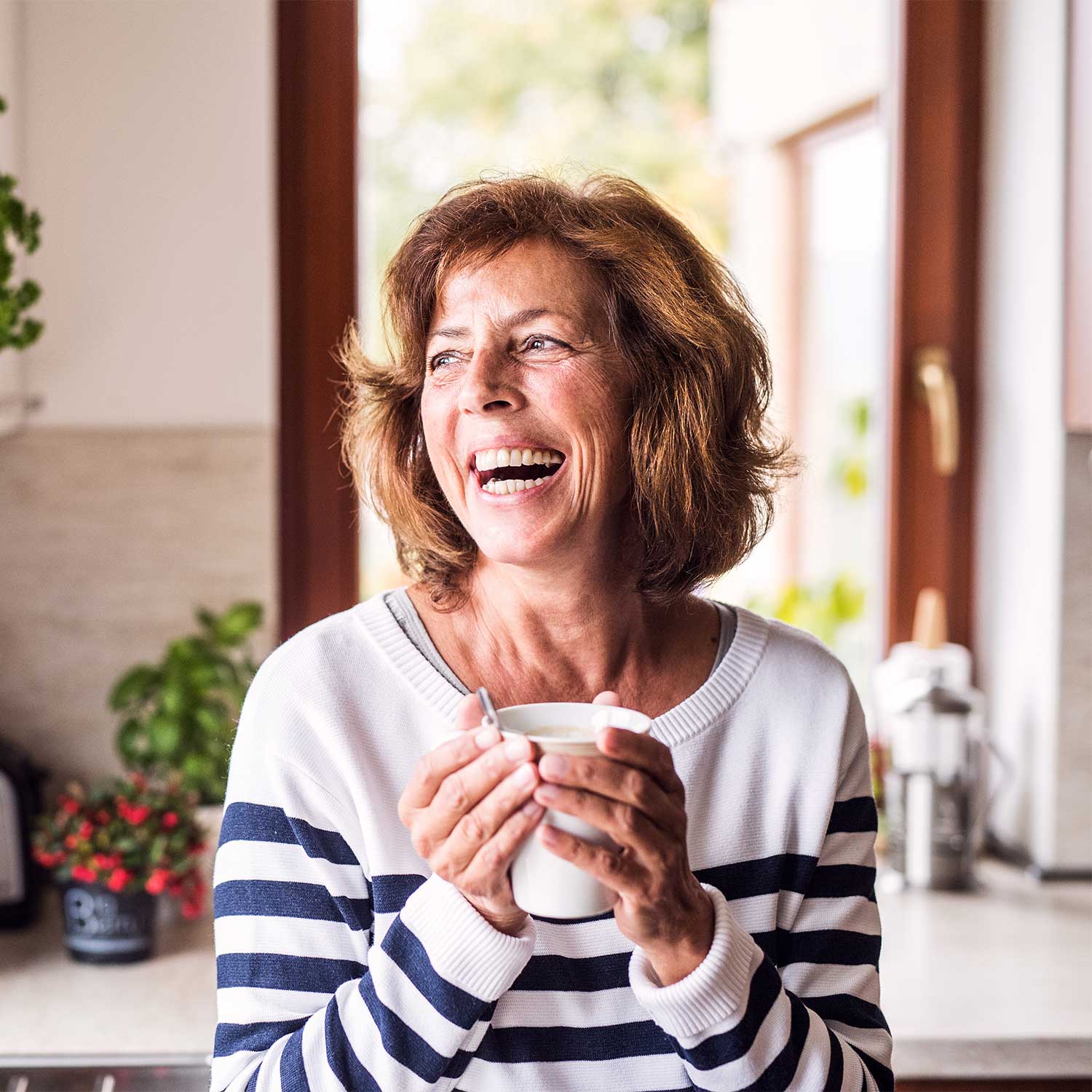 senior woman laughing holding cup of coffee